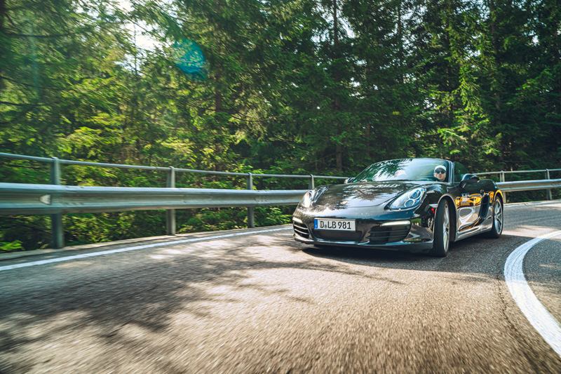 Porsche convertible on a winding forest road