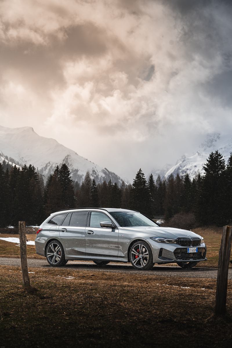 Grey BMW Touring in an alpine meadow under stormy clouds