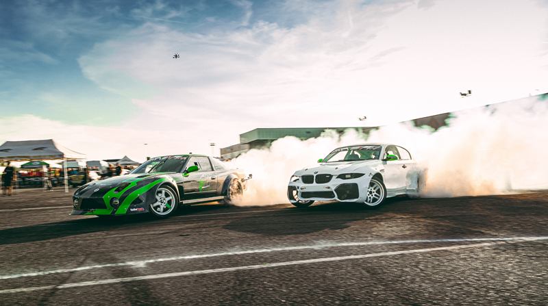 Tandem drift with tyre smoke under a blue sky